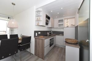 a kitchen with white cabinets and a table with chairs at Haus Oland Whg 18 in Wyk auf Föhr