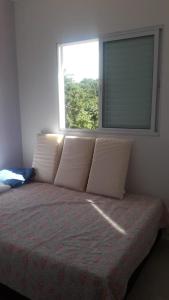uma cama com almofadas num quarto com uma janela em Chalé Isabela em Ubatuba