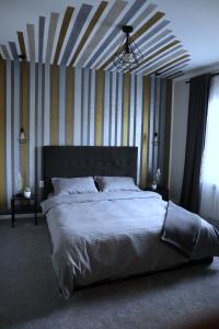 a bedroom with a large bed with a striped wall at Apartament Royal in Dej