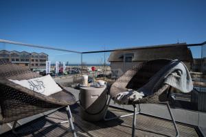a balcony with two chairs and a trash can on a roof at Ostsee - Appartement Nr 81 "Auszeit" im Strand Resort in Heiligenhafen