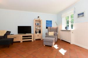 ein Wohnzimmer mit einem TV und einem Stuhl in der Unterkunft August-Endell-Weg 3 in Südstrand