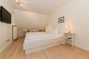 ein weißes Schlafzimmer mit einem Bett und einem Schreibtisch in der Unterkunft August-Endell-Weg 3 in Südstrand