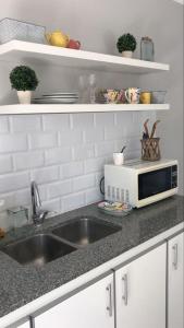 Una encimera de cocina con fregadero y microondas. en La Casita, en Carhué