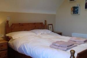 um quarto com uma cama branca e toalhas em Drumgowan House em Donegal