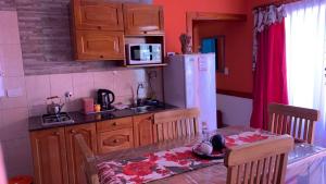 a kitchen with a table and a sink and a refrigerator at Lavanda 1 in El Calafate
