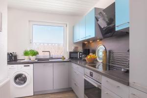 a kitchen with white cabinets and a washer and dryer at Ben in Dahme