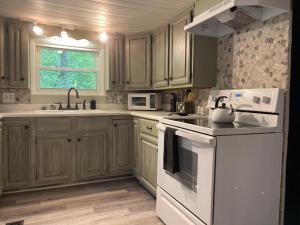 - une cuisine avec des placards en bois et des appareils blancs dans l'établissement The Hillbilly Hideaway with Hot Tub, Creek, & Outdoor Games, à Sevierville