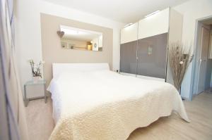 a white bedroom with a white bed and a mirror at Berolina B 102 in Dahme