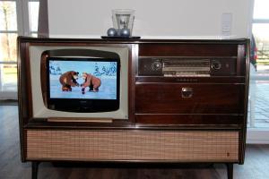 een ouderwetse televisie in een houten standaard met een beer erop bij Herrmannshof Haby App 2 Borby in Haby