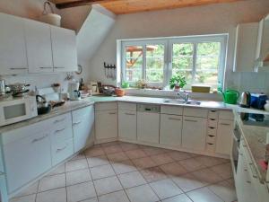 een keuken met witte kasten en een groot raam bij Drengenberg in Hanerau-Hademarschen