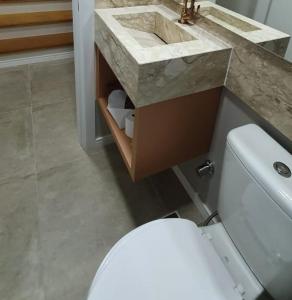 uma casa de banho com um WC branco e um lavatório. em Casa Nova Canela Condominio Fechado 40 em Canela