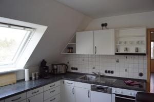 eine Küche mit weißen Schränken, einem Waschbecken und einem Fenster in der Unterkunft La Domus Premium Osnabrück Lotte in Gohfeld