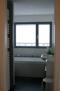 a bathroom with a large tub and two windows at Ostsee - Appartement Nr 95 "Möwe" im Strand Resort in Heiligenhafen