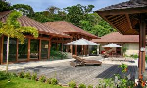 a house with a wooden deck with chairs and umbrellas at Villas by Tekoa in Uvita