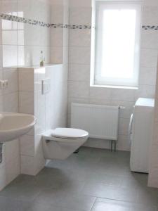 La salle de bains blanche est pourvue de toilettes et d'un lavabo. dans l'établissement Ferienwohnungen Öker - Stadtvilla OG, à Grömitz