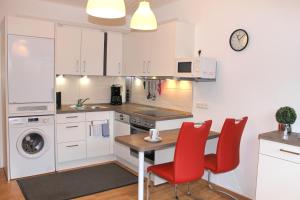 格洛米茨的住宿－"Wohnung 1 - G Pape" mit 2 Terrassen, kostenloses WLAN, Longstay Rabatt, Nähe Dünenpark，厨房配有桌子和红色椅子