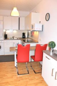 格洛米茨的住宿－"Wohnung 1 - G Pape" mit 2 Terrassen, kostenloses WLAN, Longstay Rabatt, Nähe Dünenpark，厨房配有红色的椅子和桌子