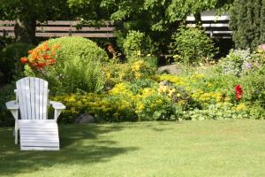 a white chair sitting in a garden with flowers at Muschelkorb in Hinrichsdorf