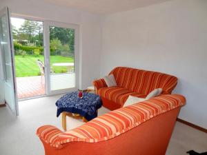 un soggiorno con 2 divani arancioni e un tavolo di FeWo im Schobeck a Hanerau-Hademarschen