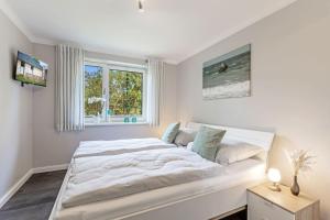 a white bedroom with a large bed and a window at Relax Bungalow Strandperle in Klausdorf