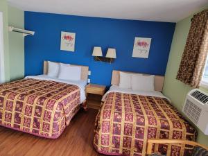 2 letti in una camera d'albergo con pareti blu di Plaza Motel a Joplin