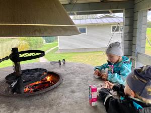 a couple of children sitting around a fire pit at Huoneistomajoitus Koto, LaatuLomat in Juva