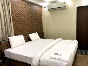 a bedroom with two beds with white sheets at Meenakshi Inn in Udupi