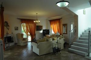 a living room with a couch and chairs and stairs at Bella Villa in Vaia