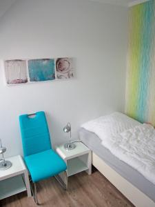 a bedroom with a bed and a blue chair at "Landhaus Voss" Typ 4 Nr11 in Staberdorf