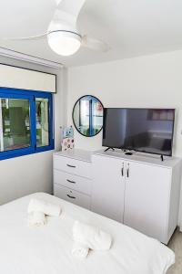 a white bedroom with a flat screen tv and a bed at דירת גן פונה לבריכה - pool garden view eilat in Eilat