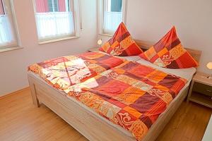 ツィングストにあるSonnenpalaisのベッドルームにカラフルなキルトのベッド1台が備わります。
