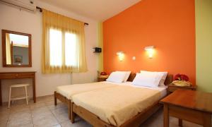 een slaapkamer met een groot bed met een oranje muur bij Nama Apartments in Skala Potamias