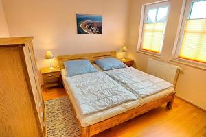 a bed in a bedroom with two lamps and two windows at Gerlach in Zingst