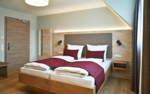 a bedroom with a large bed with red pillows at Hotel Restaurant Klosterhof in Gutenzell-Hürbel