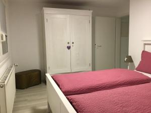 オッフェンブルクにあるFerienwohnung Casa Biancaのピンクベッドとキャビネット付きのベッドルーム1室が備わります。