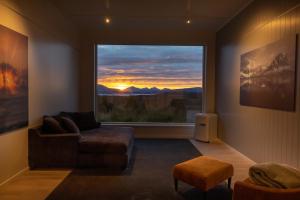 a living room with a couch and a large window at Aurora Borealis Observatory in Silsand