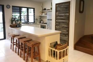 a kitchen with a counter with stools and a counter top at LILY LAMOND, T/House, outdoor shower, 5 min walk to the ocean, Airlie Beach in Airlie Beach