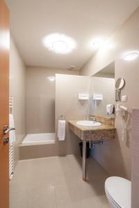 a bathroom with a sink and a toilet and a tub at Das Blaufränkisch Weinhotel & Restaurant in Girm +25 photos