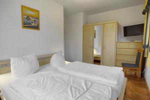 sypialnia z białym łóżkiem i krzesłem w obiekcie Villa "Meereslust" , Whg 1 w Zingst