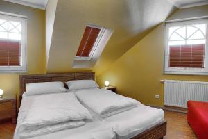 a bedroom with a large white bed with two windows at Villa Sonnenuhr, FW 8 in Zingst