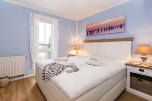 a bedroom with a white bed and a window at Whg 13 - De Fischer un sin Fru in Zingst