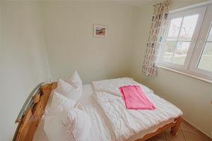 Schlafzimmer mit einem Bett mit weißer Bettwäsche und einem Fenster in der Unterkunft Am Deich 09 in Zingst