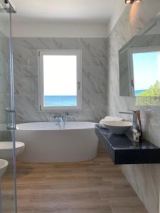 a bathroom with a tub and a sink and a window at Villa Blanca del mar in Quartu SantʼElena +3 photos