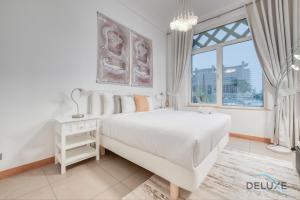 Lively 1 BR at Al Nabat Shoreline 8 Palm Jumeirah by Deluxe Holiday Homes في دبي: غرفة نوم بيضاء مع سرير كبير ونافذة
