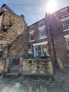 a brick building with a blue door on it at Dunsley Cottage in Staithes