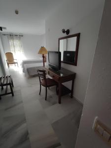 a living room with a desk with a tv and a mirror at Hotel Cervantes in Badajoz +9 photos