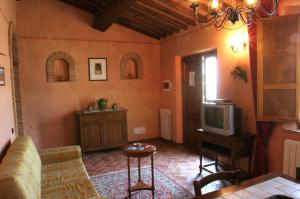 ein Wohnzimmer mit einem Sofa und einem TV in der Unterkunft Agriturismo Renaccino in Siena