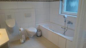 baño blanco con bañera y aseo en FeWo-Neustadt-Pfitz en Neustadt in Holstein