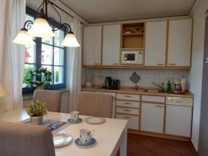 una cocina con armarios blancos y una mesa con sillas. en Eichenpark 33, en Prerow