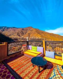 einen Balkon mit einem Sofa, einem Tisch und einem Berg in der Unterkunft Riad Atlas Toubkal in Imlil